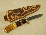 Roger does it again, another fine melding of brass, antler, leather, spacers, and damascus.  Hand carved sheath by Roger too.